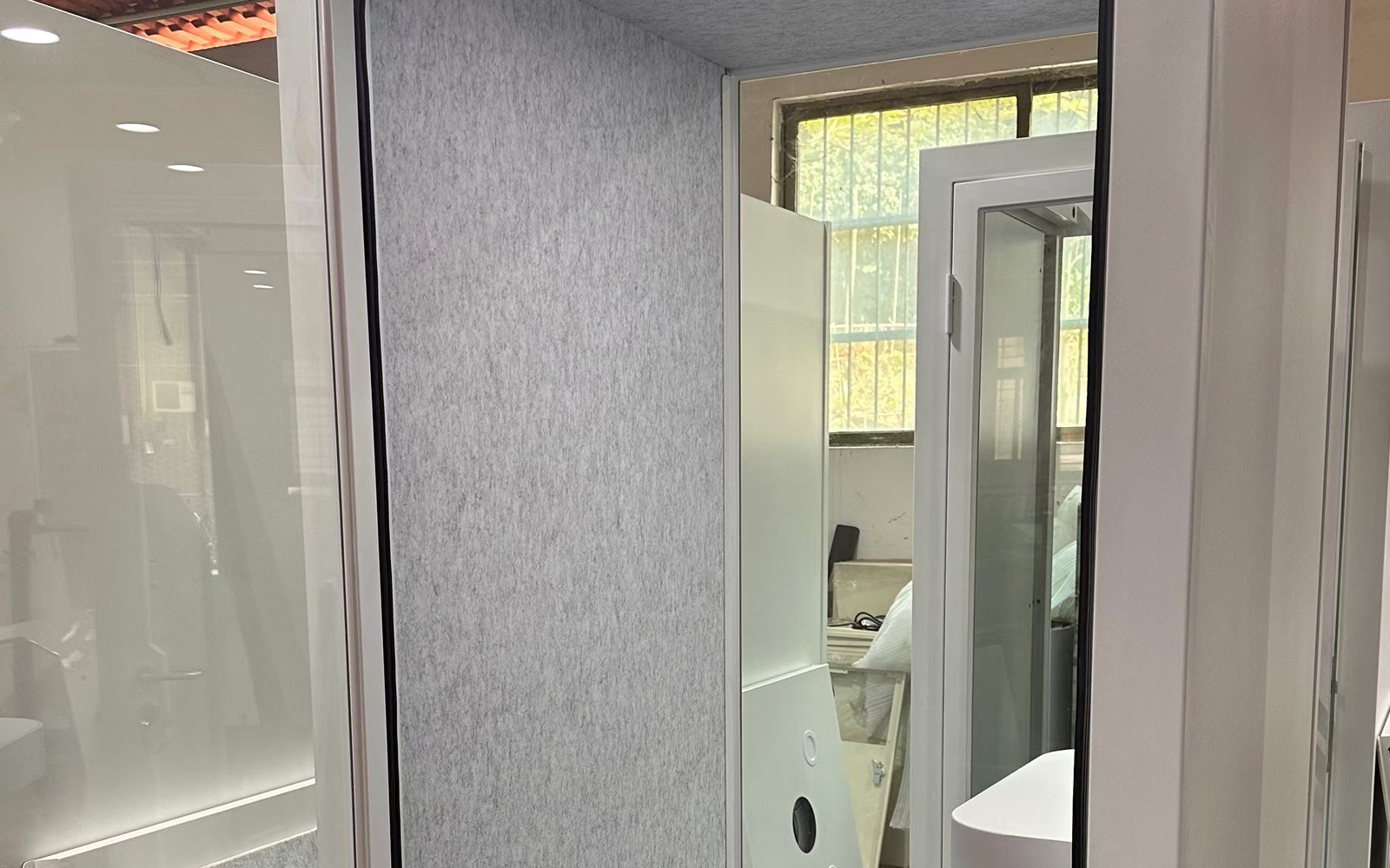 Textured grey pod wall panel beside white door frames and glass