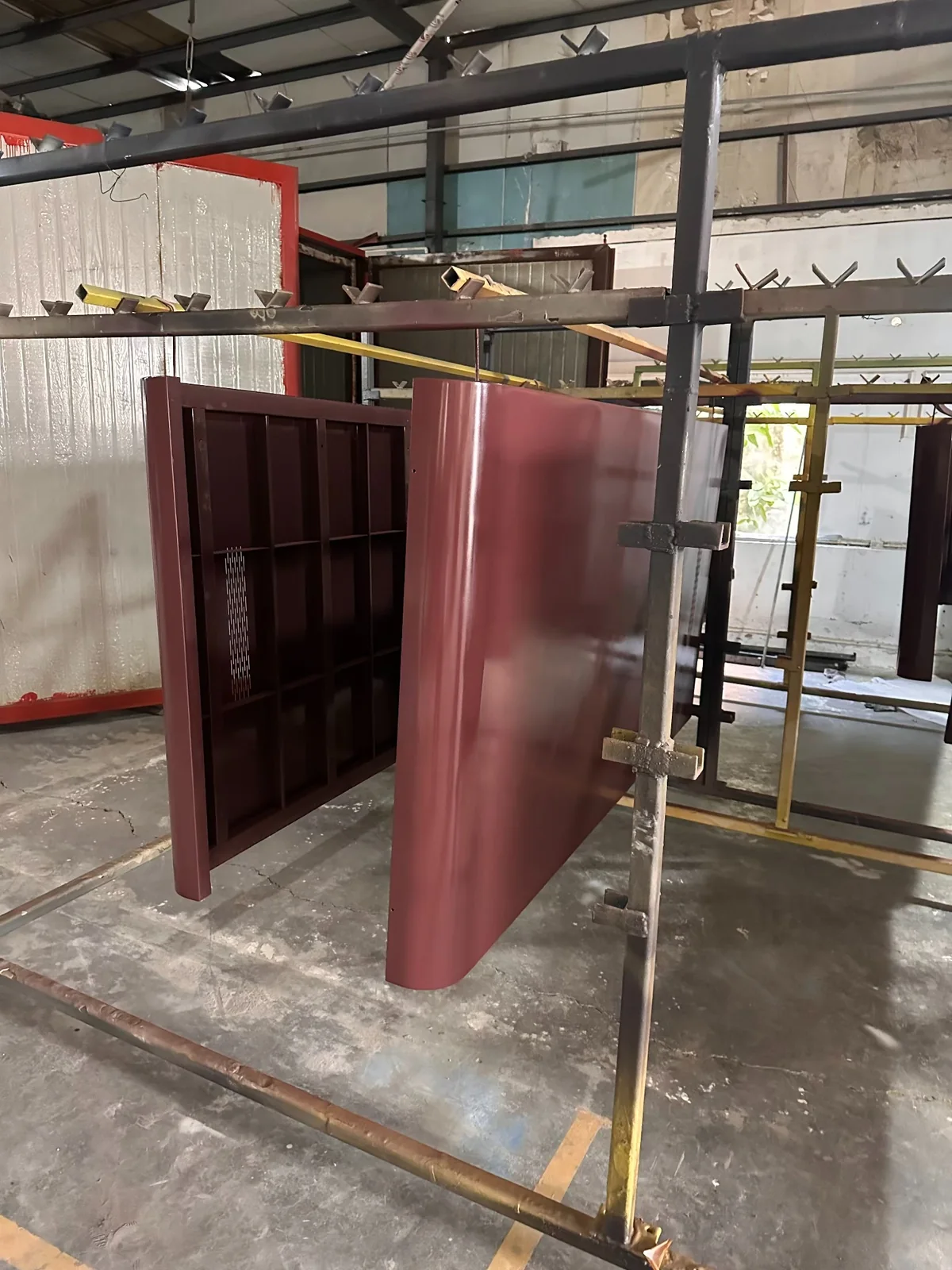 Front and reverse sides of burgundy-colored office pod panels on factory racks