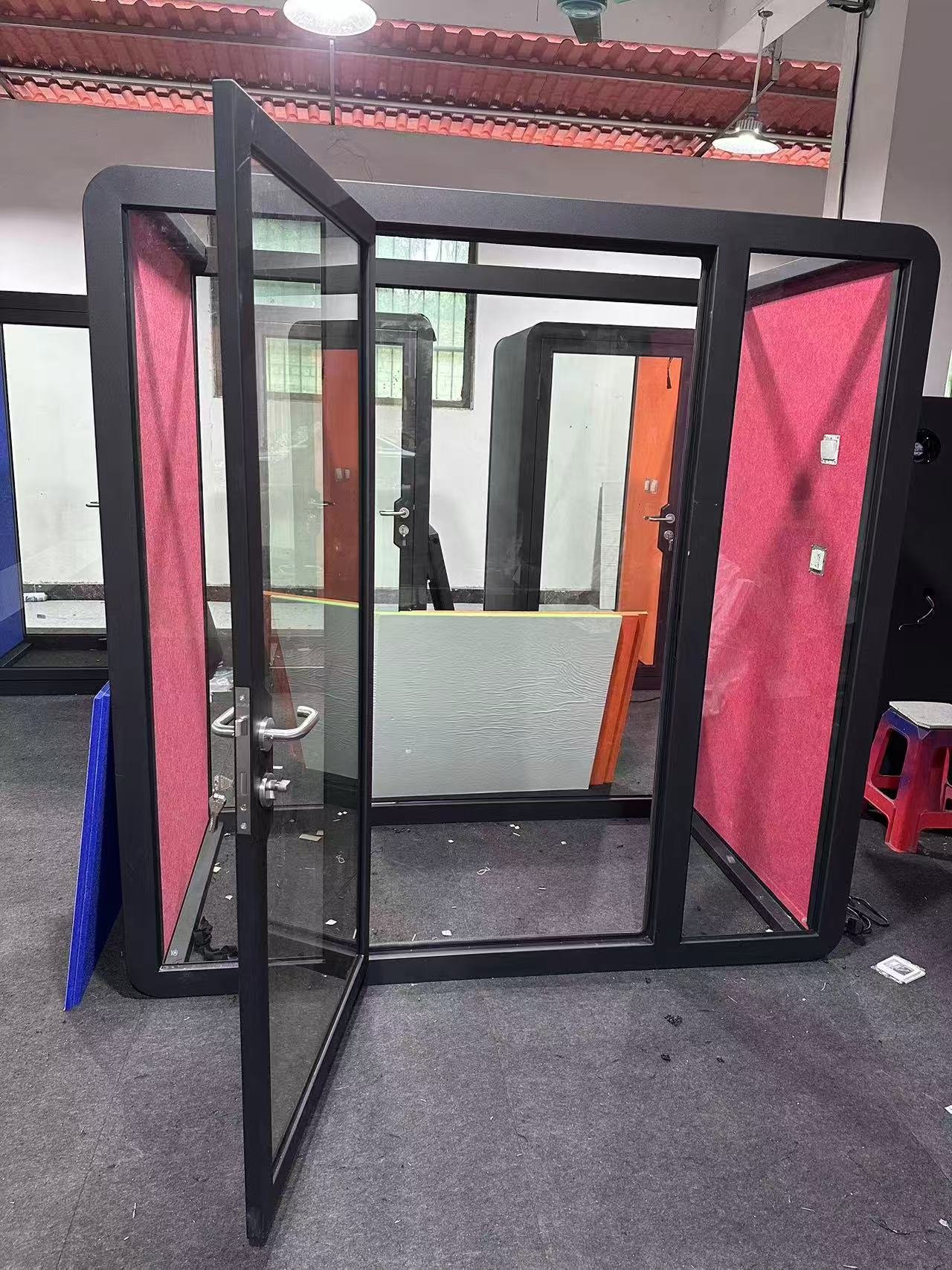 Factory-stage office pod entrance with an open glazed door and metal handle